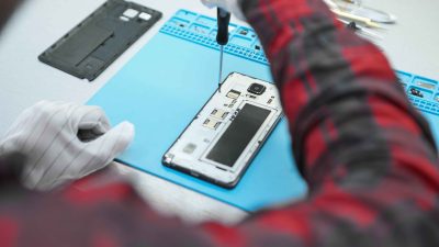 A professional technician is removing screws of mobile